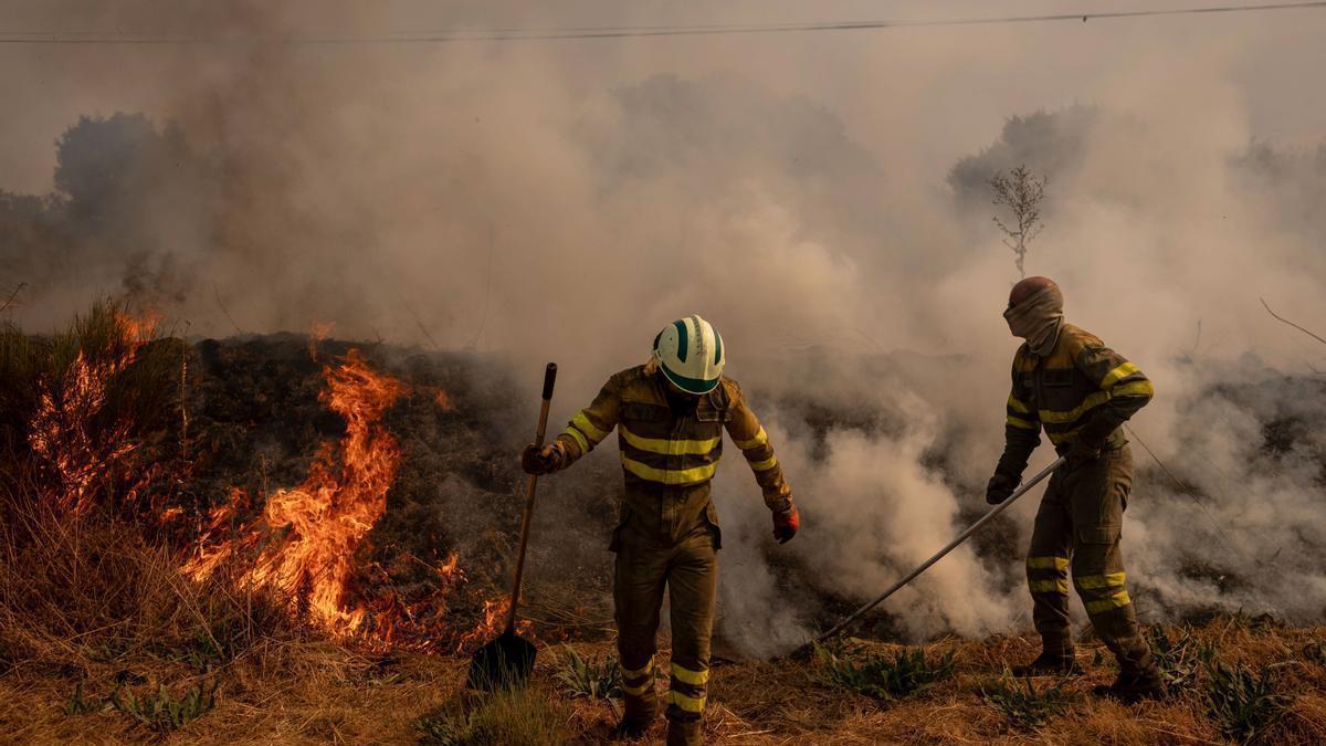 Dos voluntarios realizan labores de extinción en el incendio de Oímbra, Ourense.