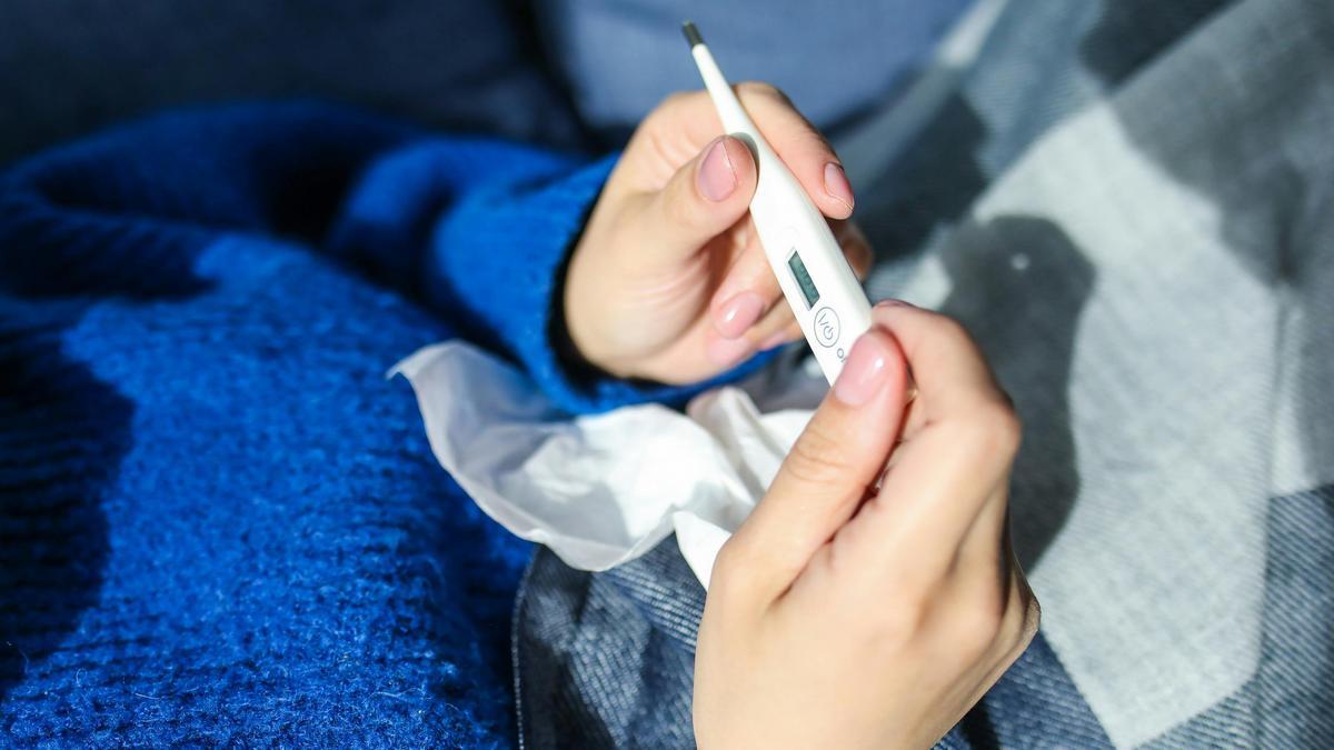 Una persona con un termómetro y un pañuelo en la mano.