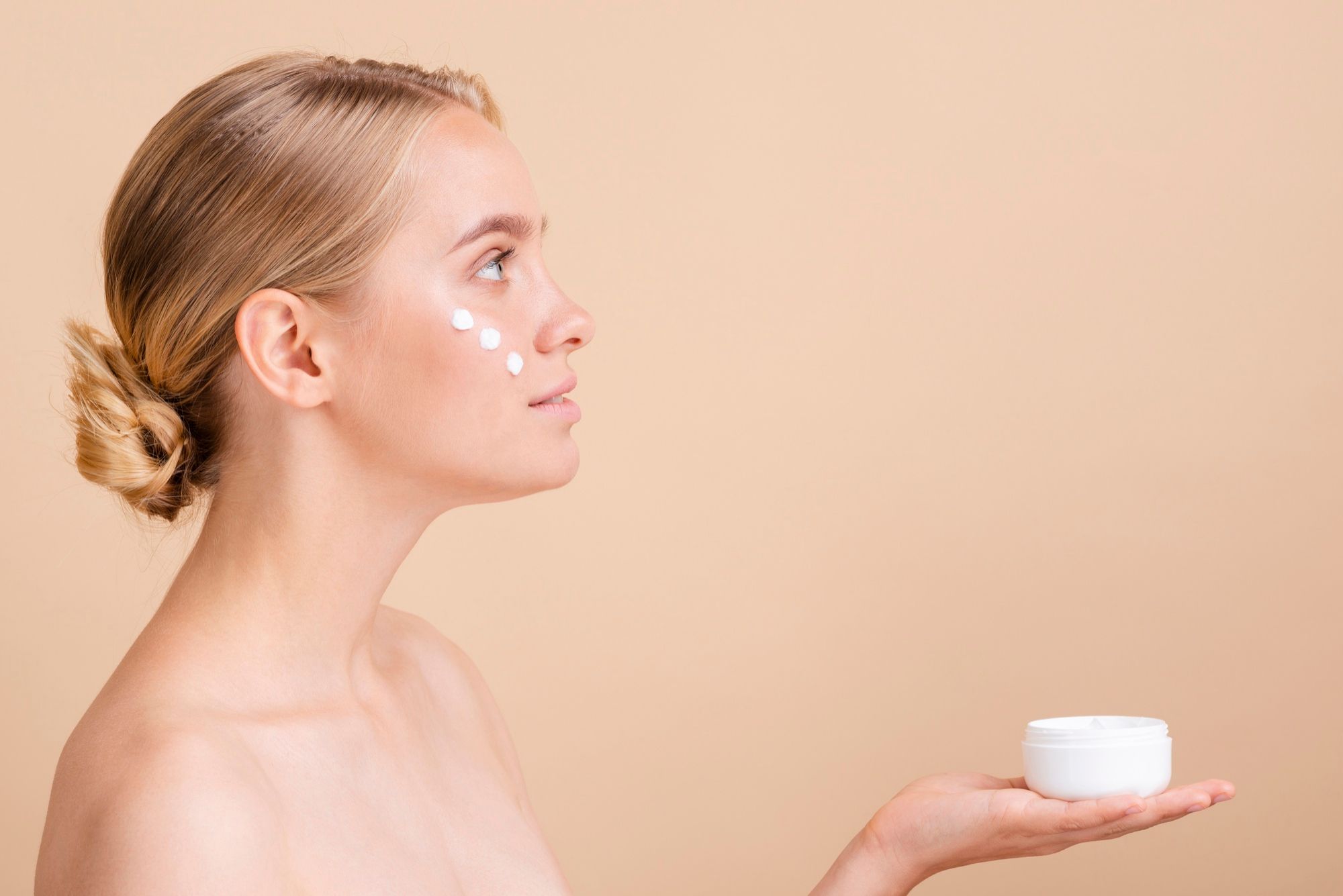 Mujer se aplica crema en el rostro