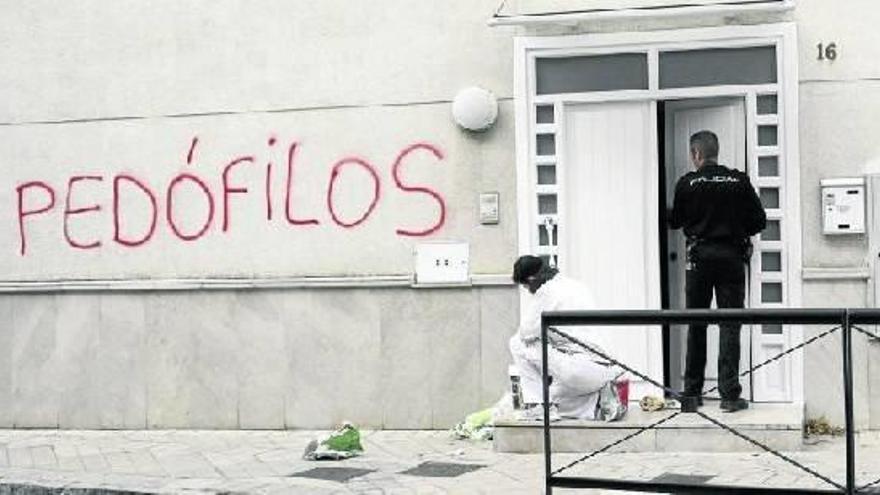 Un operario limpia las pintadas contra los curas acusados a busar sexualmente de un menor en Granada.