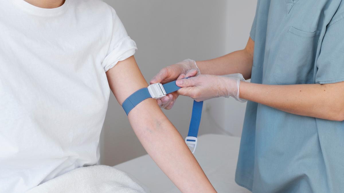 Una enfermera coloca la goma en el brazo antes de extraer sangre.