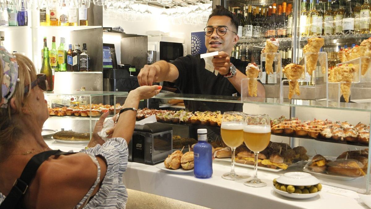 Un camarero atiende a una clienta en el bar.