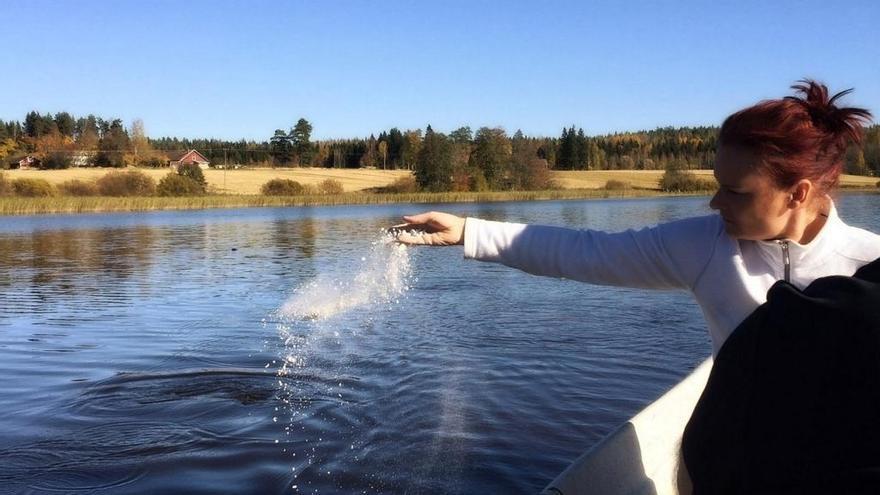 Una mujer esparce cenizas en un lago. Una mujer esparce cenizas en un lago.
