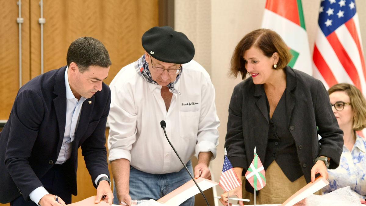 El lehendakari, Imanol Pradales; el presidente de NABO, Jean Flesher; y la responsable de Etxepare Institutua, Irene Larraza, firman el acuerdo para reforzar el euskera en las Euskal Etxeak