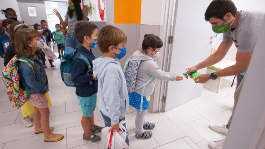 Niños con mascarilla acceden al aula tras echarse gel