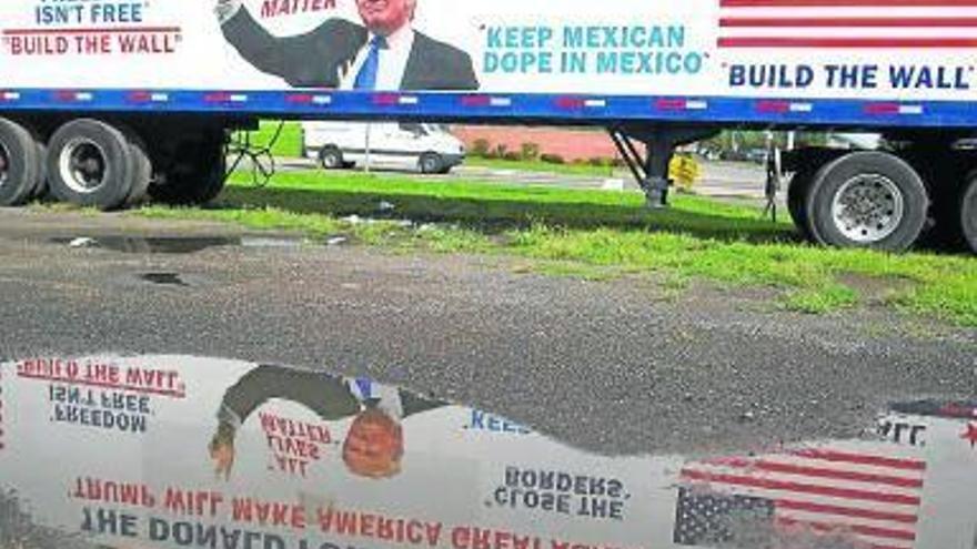 Los mensajes pro-fronteras de Trump se reflejan en un charco.