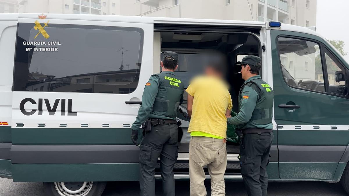 Dos agentes de la Guardia Civil introducen en una furgoneta a un detenido por su presunta implicación con la banda Trinitarios.