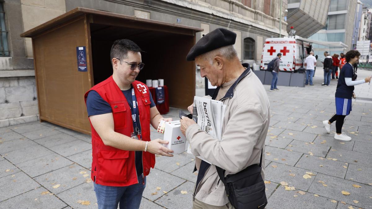 Un hombre aporta un donativo en una de las huchas de Cruz Roja