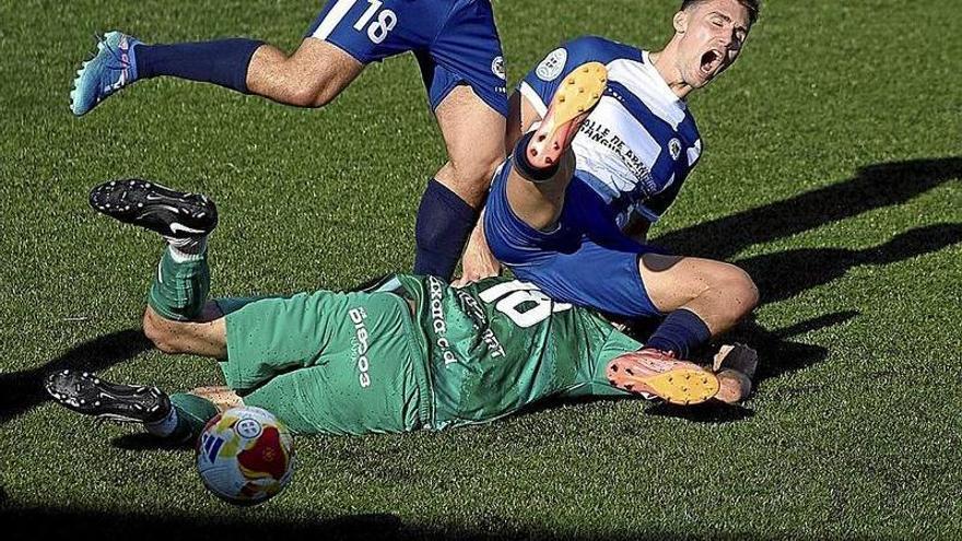 Iñaki Berruete (San Juan) se va al césped al luchar un balón contra dos jugadores del Cirbonero .