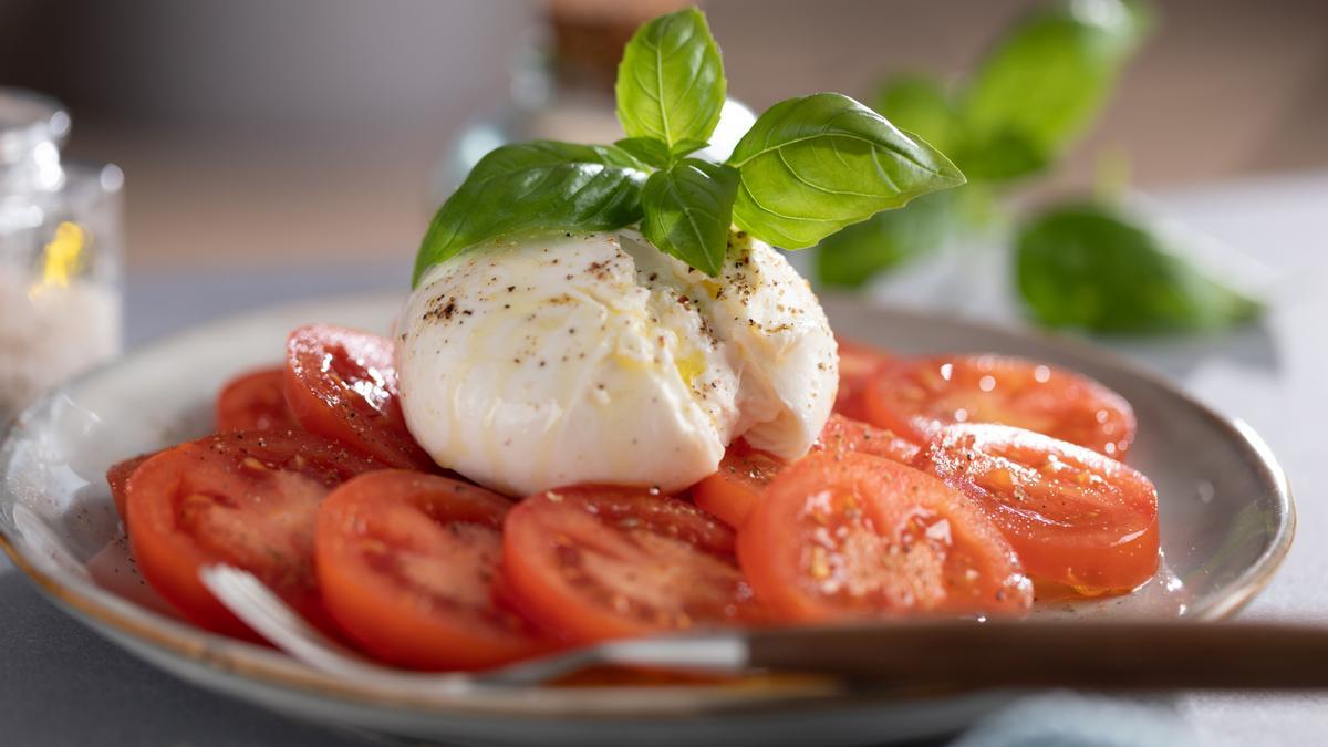 Una ensalada de tomate con burrata y albahaca.