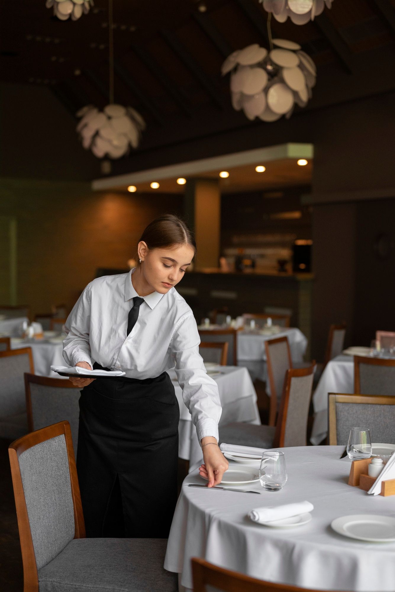 Una camarera prepara una mesa en el comedor de un hotel.