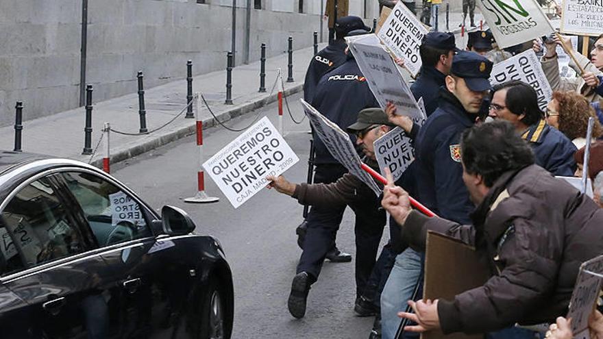 Un grupo de personas protesta a la llegada del exministro del Interior y expresidente de la comisión de auditoría de Bankia, Ángel Acebes, a la Audiencia Nacional.