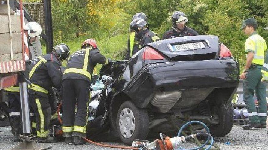 Los bomberos tratan de rescatar los cuerpos atrapados en el interior del vehículo.