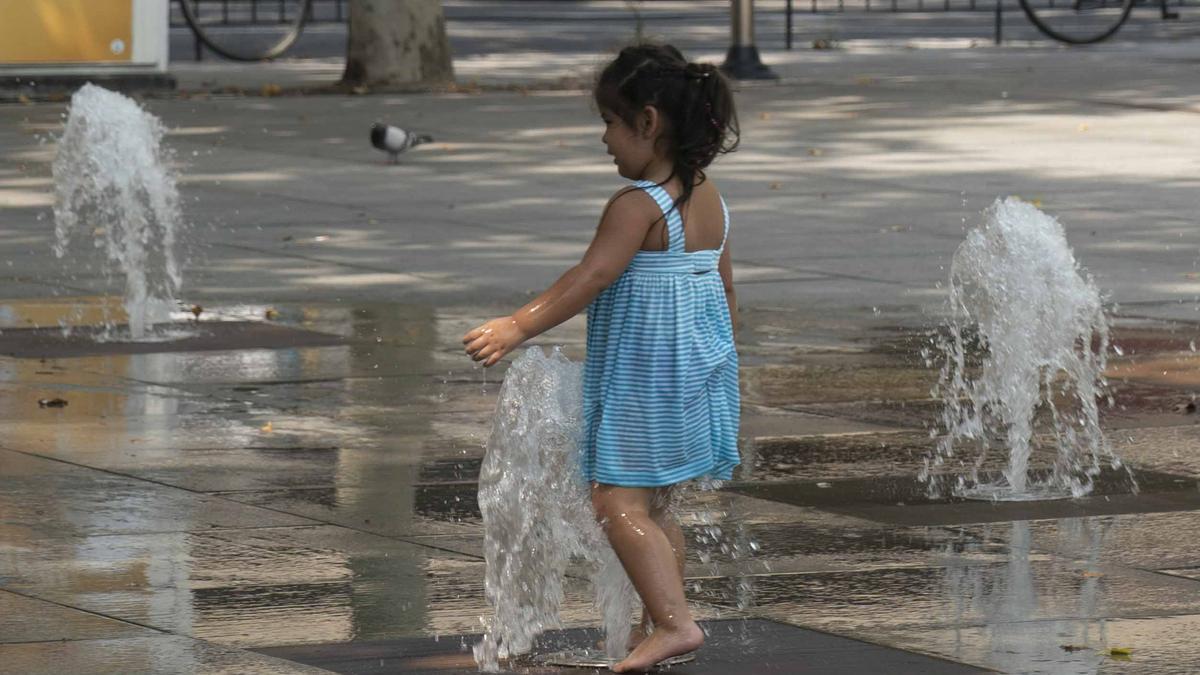 Una niña se refresca en una fuente de Vitoria durante una calurosa jornada de este verano