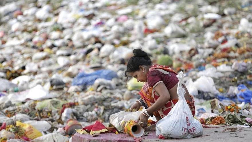 Una mujer recoge residuos depositados por devotos en la orilla del río Ganges, en Calcuta (India).
