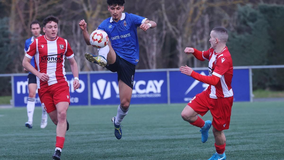 Imanol Satrústegui trata de controlar el balón ante la atenta mirada de dos rivales