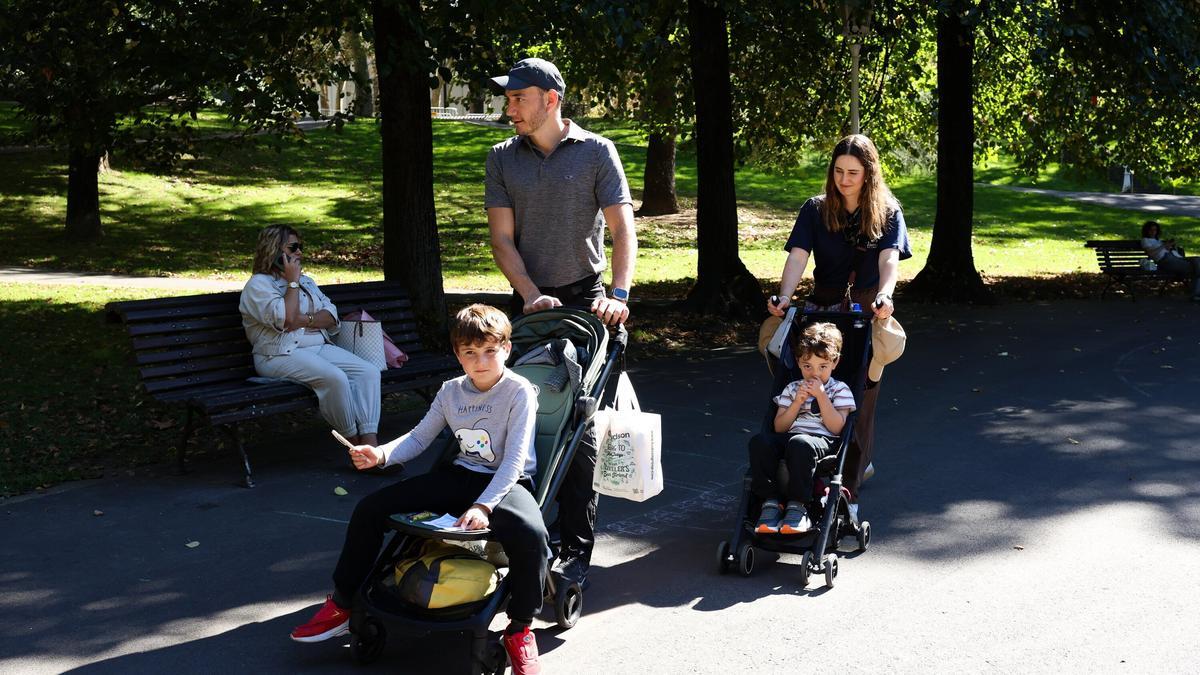 Padres pasean con sus hijos en el parque de Doña Casilda.