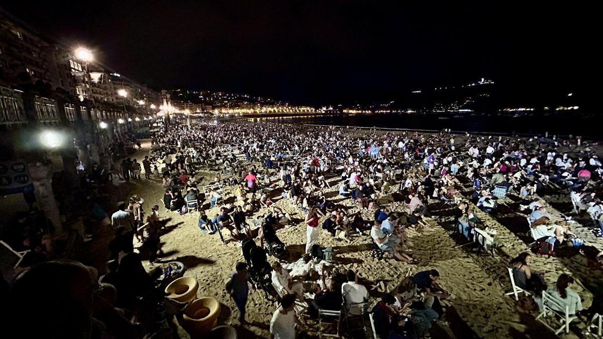 Gente esperando en la playa para ver los fuegos artificiales