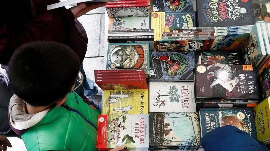 GRAFCAV3757. PAMPLONA (NAVARRA), 23/04/2019.- Un niño escoge un libro en uno de los puestos instalados por varias librerías de Pamplona que participan con sus casetas en la Feria del Libro y de la Flor que se instala en la confluencia de la avenida de Car