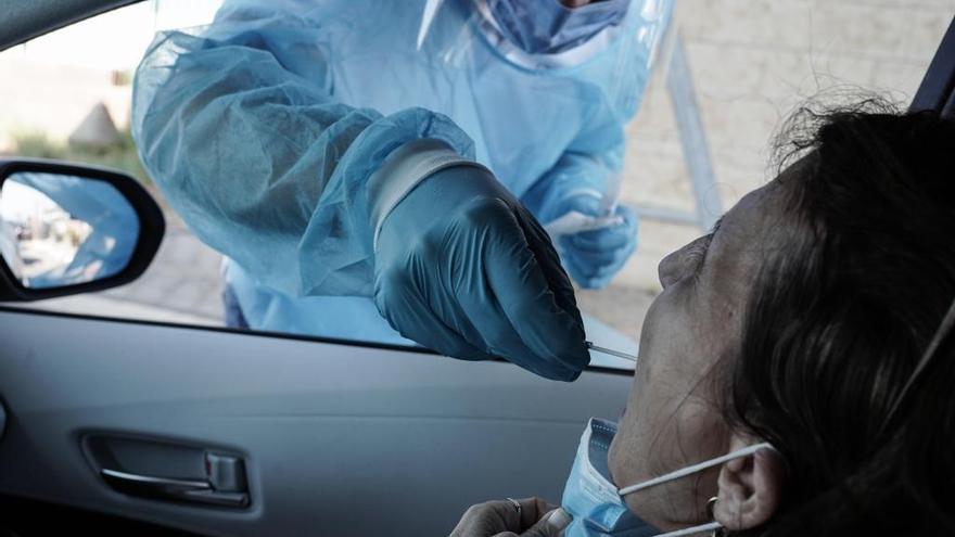 Un trabajador de la salud toma un hisopo de una mujer para una prueba de PCR de coronavirus.