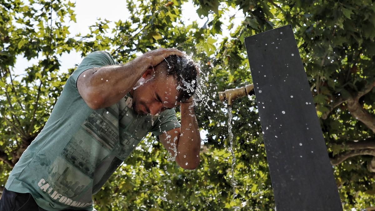 Una persona se refresca en una fuente en Pamplona en una jornada tórrida de agosto.