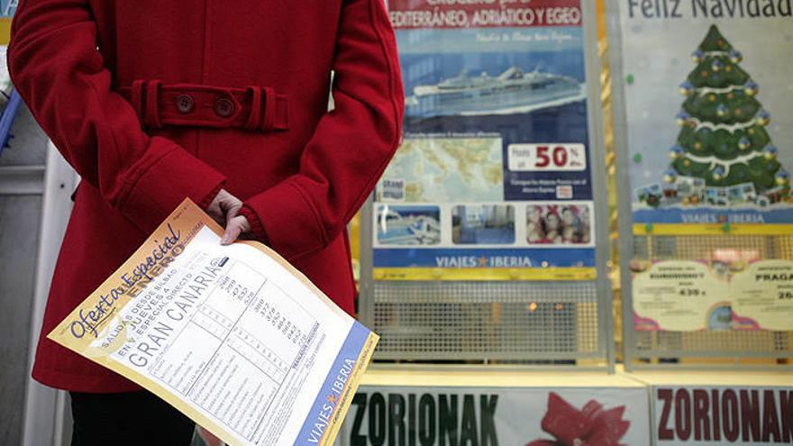 Mujer ante el escaparate de Viajes Iberia con un folleto de ofertas de viajes