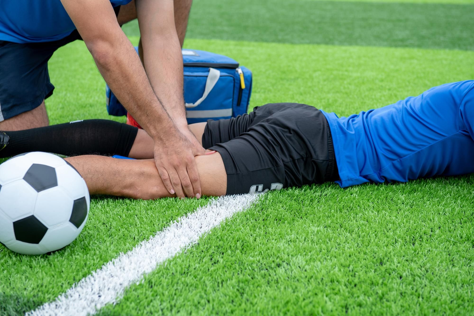 Un jugador lesionado recibe atención en el suelo.