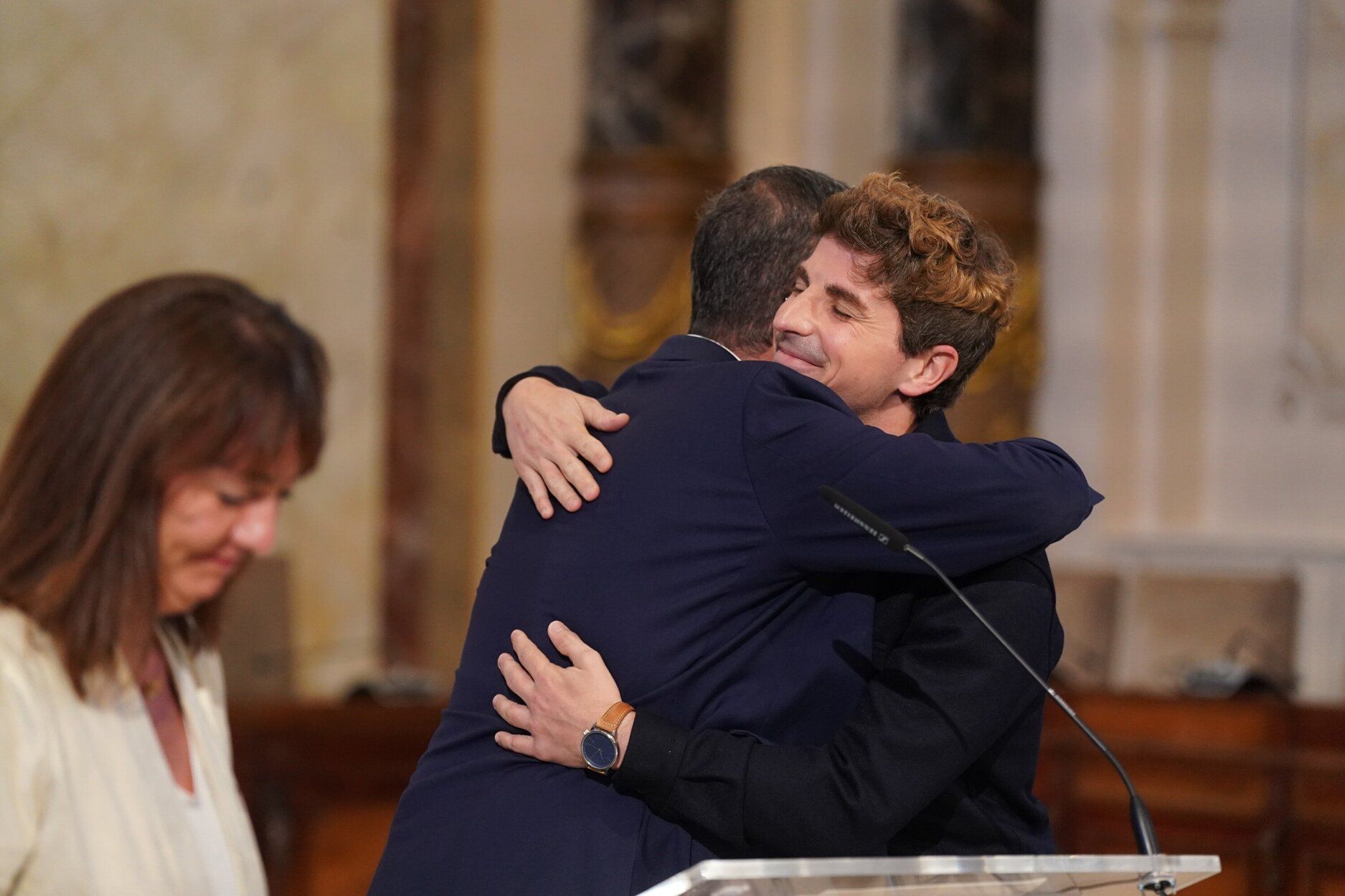 El edil de Cultura, Jon Insausti, abraza al alcalde de Donostia, Eneko Goia, tras la comparecencia en la que ha anunciado su adiós