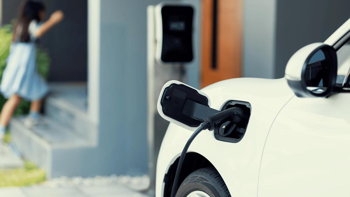 Coche eléctrico aparcado y cargando frente a una vivienda