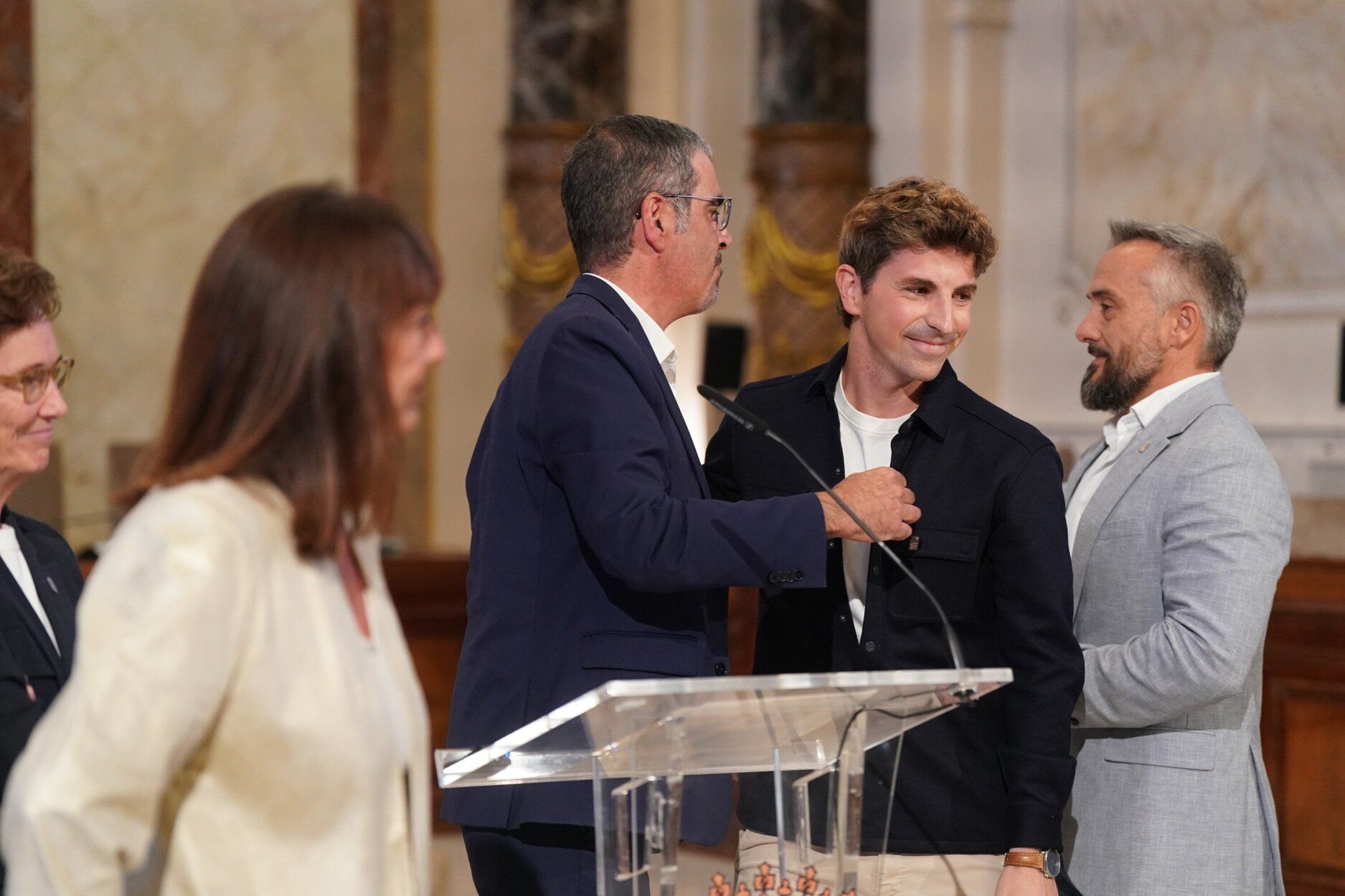 El edil de Cultura, Jon Insausti, abraza al alcalde de Donostia, Eneko Goia, tras la comparecencia en la que ha anunciado su adiós