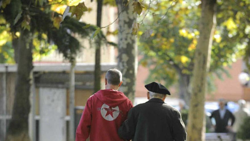 Un cuidador pasea con una persona mayor.