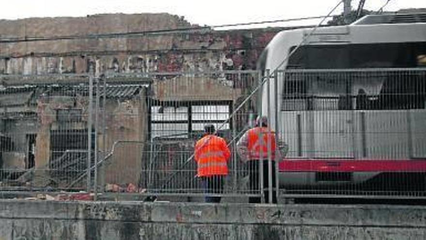 Dos operarios del metro observan la fachada del edificio.