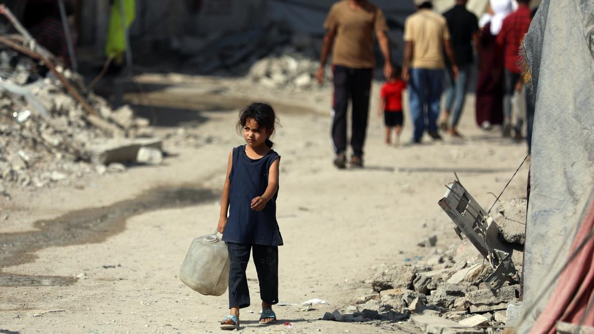 Una niña en Gaza caminando con un bote de agua bajo el calor.