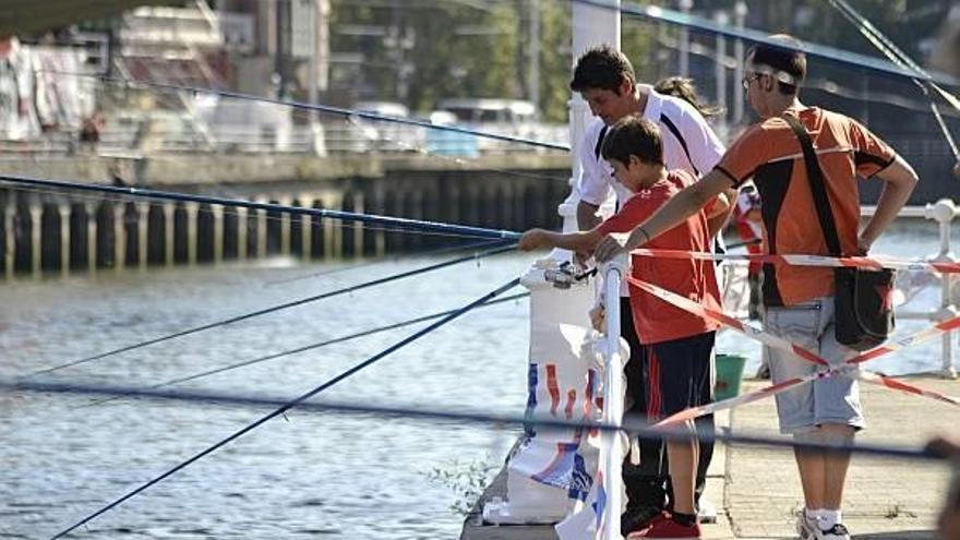 Uno de los monitores enseña cómo pescar a un niño.