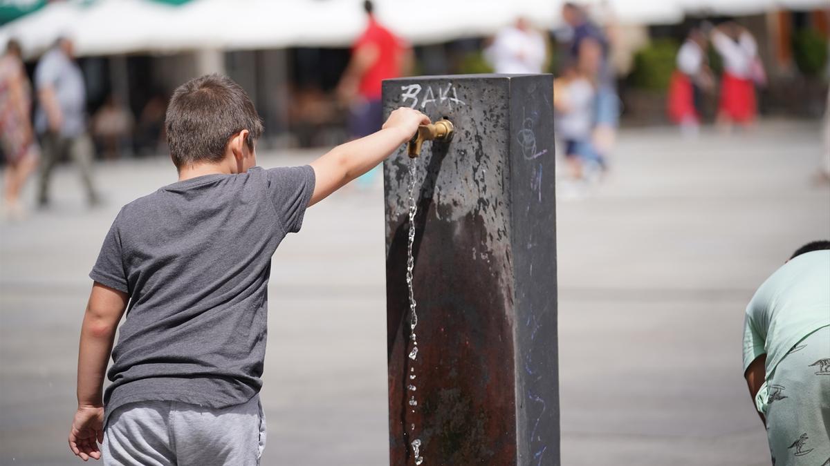 Un niño llena usa una fuente para refrescarse.