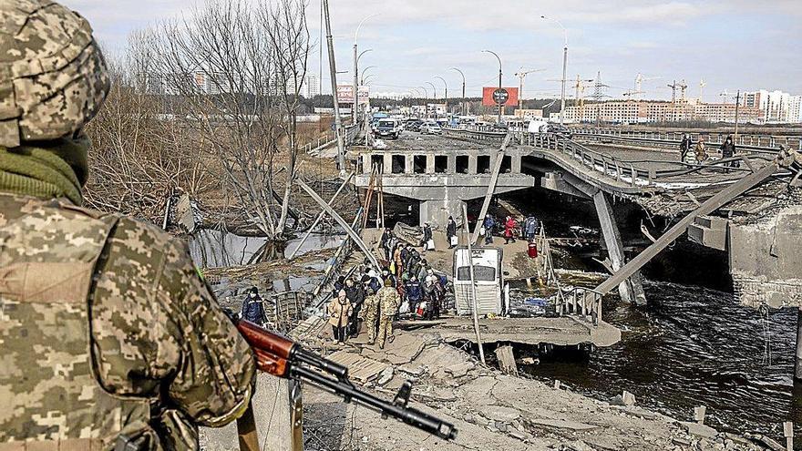 Un soldado ucraniano observa la evacuación de civiles a través de un puente destruido en Irpin.