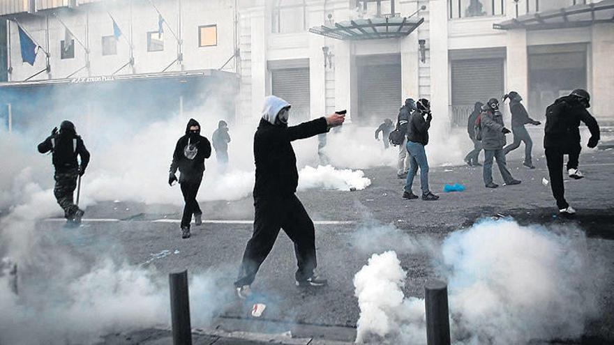 Un manifestante esgrime lo que parece una pistola (probablemente, de bengalas) y apunta hacia la policía en medio de graves disturbios que tuvieron ayer en Atenas.