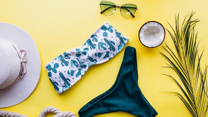 Bikini colocado junto a accesorios de playa como un sombrero o unas gafas de sol.