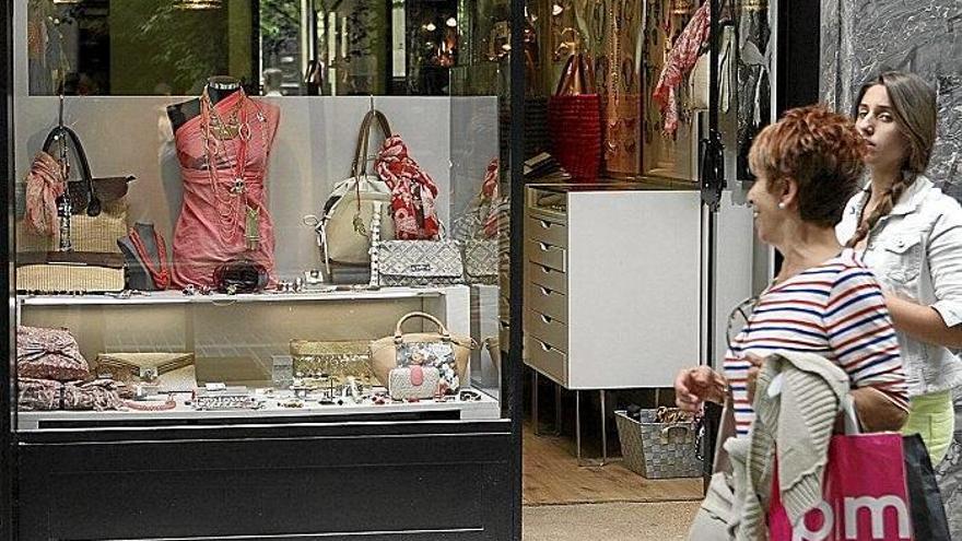 Dos mujeres caminan por delante del escaparate de una tienda en el centro de la capital guipuzcoana.