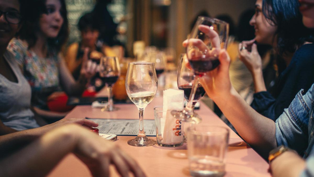 Personas bebiendo vino y conversando en una mesa.
