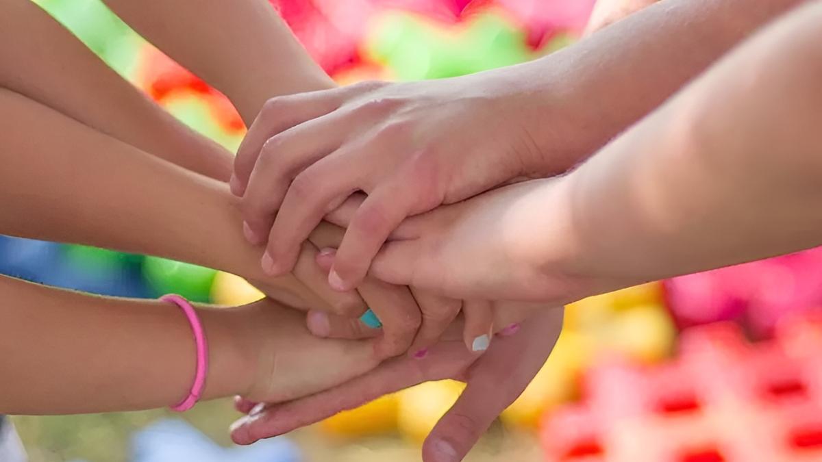 Un grupo de niños y niñas uniendo las manos.