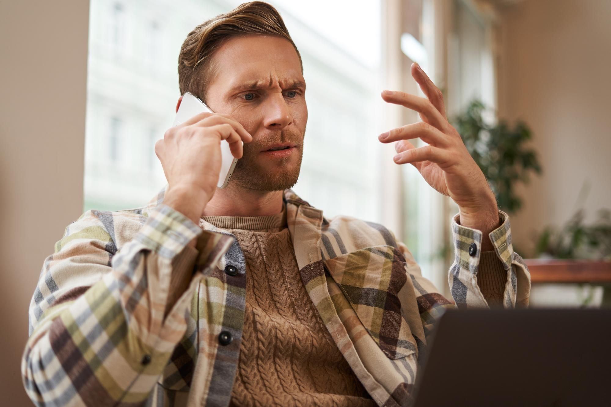 Un hombre habla por teléfono con gesto de enfado.