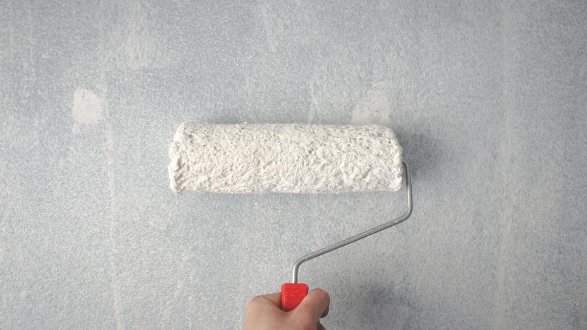 Una persona pintando una pared con un rodillo.