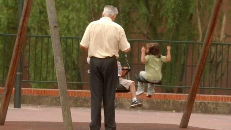 Un abuelo acompaña a sus nietos en un parque.