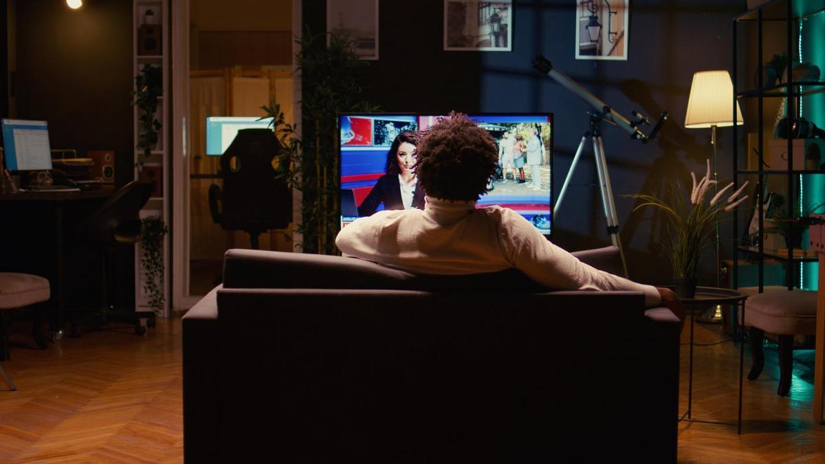 Una persona ve la televisión en el salón de su casa. Una persona ve la televisión en el salón de su casa.