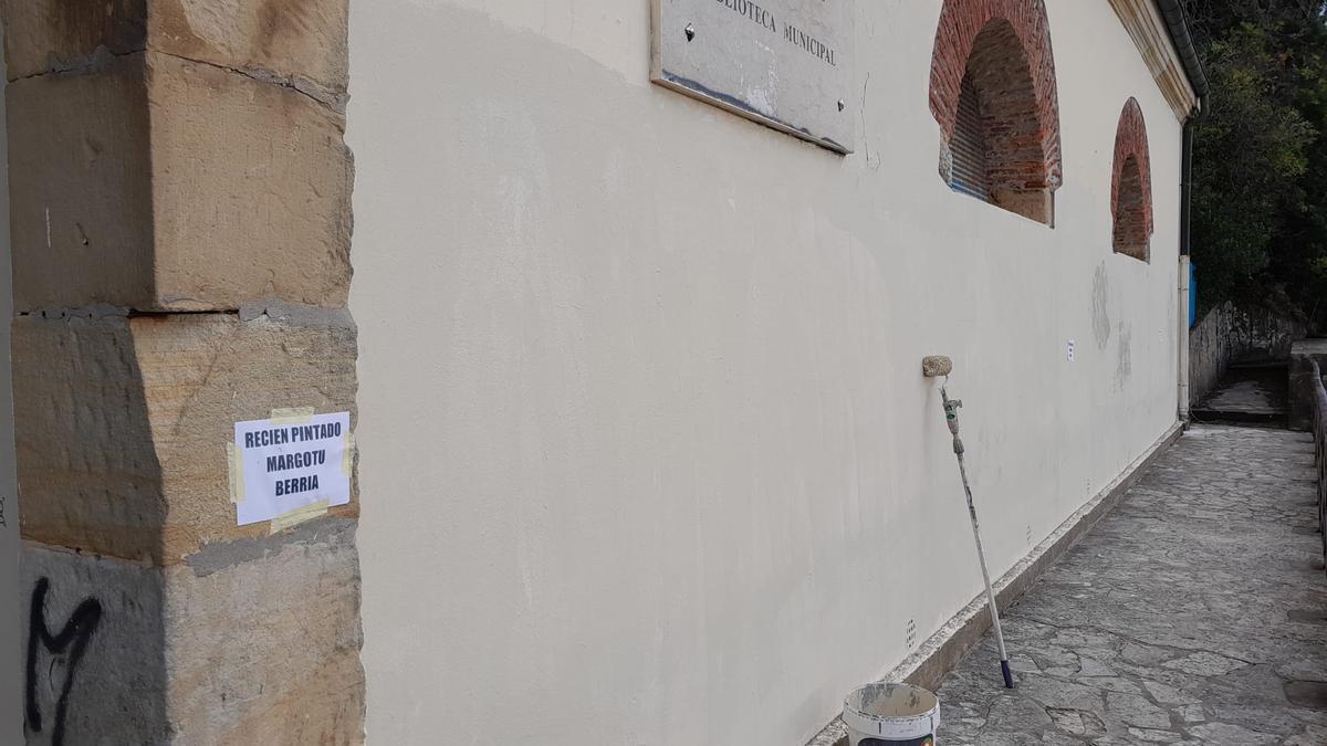 Una cartel indica que la pared ha sido recién pintada tras borrar el grafiti