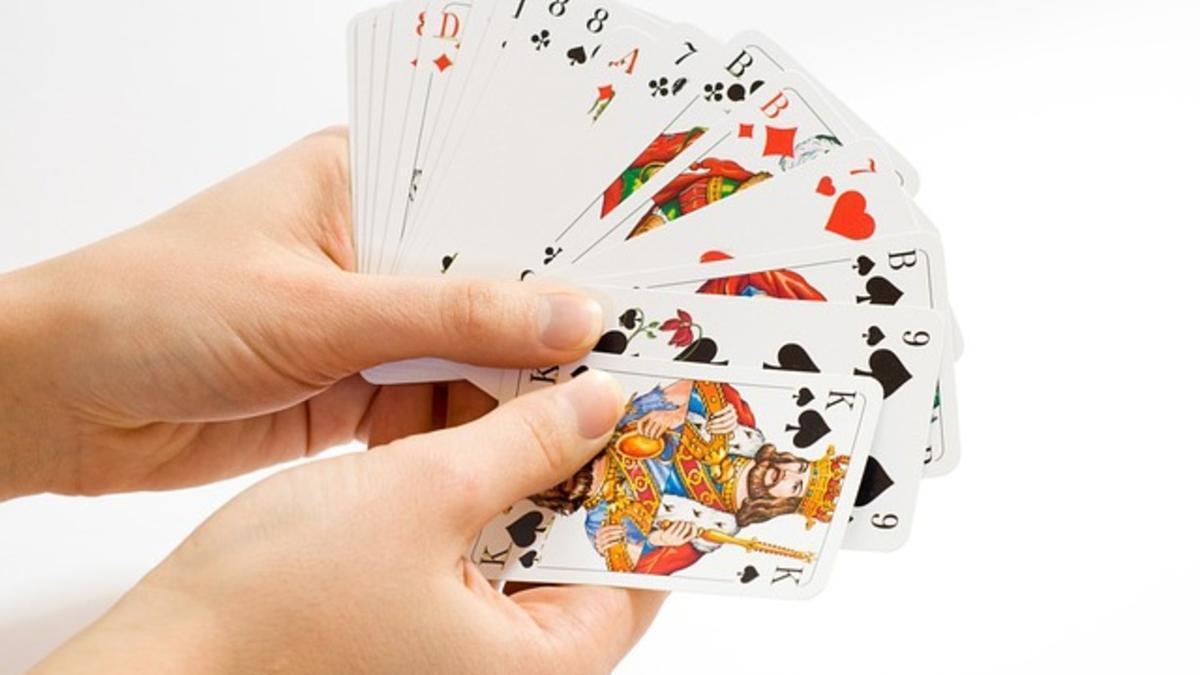 Una persona examina su baraja al jugar a las cartas.