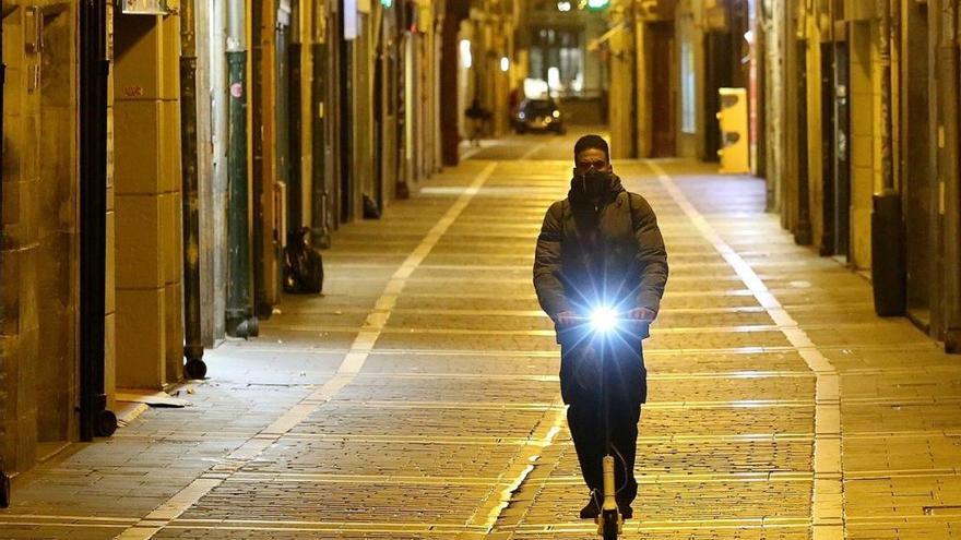 Un joven circula de noche con un patinete eléctrico.