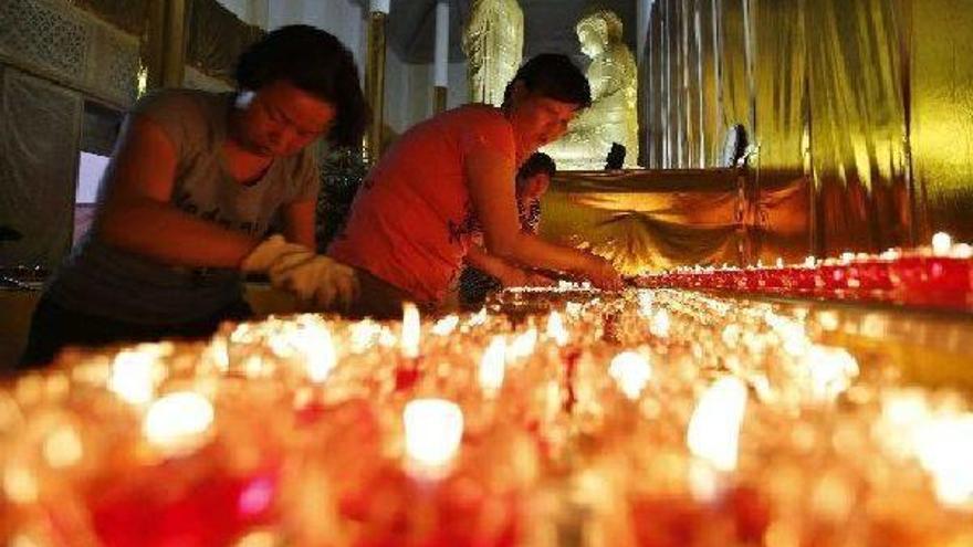 Varias personas encienden velas mientras rezan por las víctimas de la explosión.