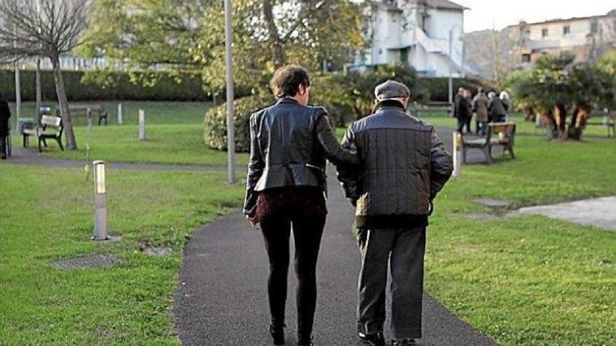 Una cuidadora paseando con un anciano